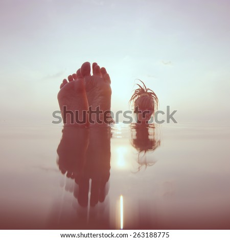 girl in the sea at sunset. unusual perspective portrait. vintage color style
