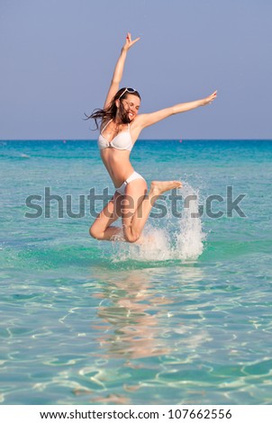 A laughing woman is jumping in water