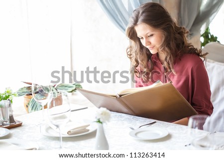 A smiling woman in a restaurant with the menu in hands