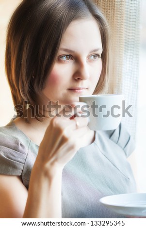 A smiling woman in a restaurant is drinking coffee