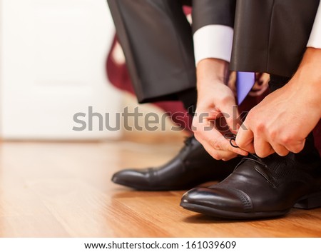 Man is tying his black shoes. Close-up