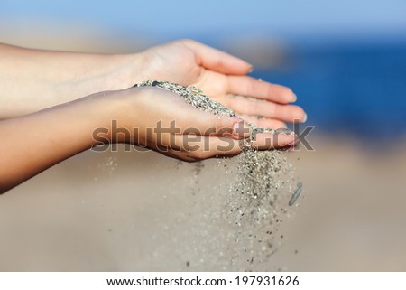 A woman with sand falling through her hands. Close-up