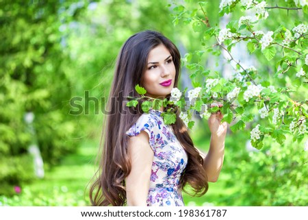 Young woman is posing near blooming tree