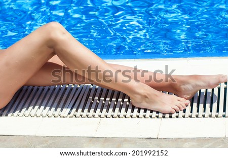 Sexy legs of woman lying near the pool