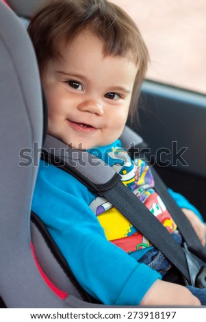 Portrait of cute smiling little girl sitting in her car safety seat