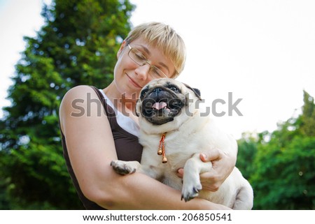 Nice blonde and cheerful young woman hugging her dog in the summer park.