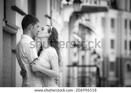 Happy couple walking on a street, hugging and kissing. Black-and-white portrait.