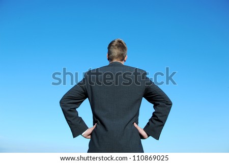 Businessman in control. Dark suit and blue sky. / In Control