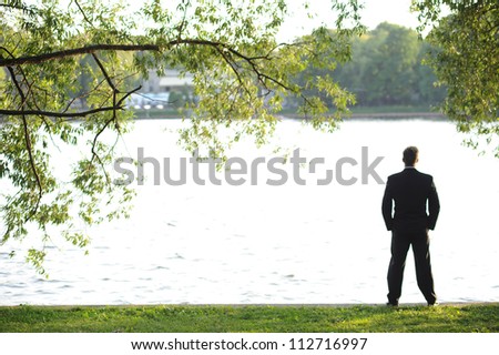 Young businessman looking at the river in the evening sun.