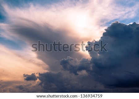 Menacing sky with clouds and sun emerging through translucent clouds