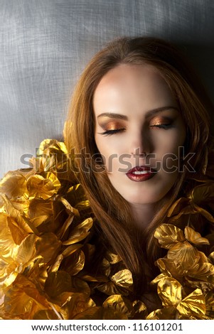 Beautiful red haired woman with gold makeup and flowers