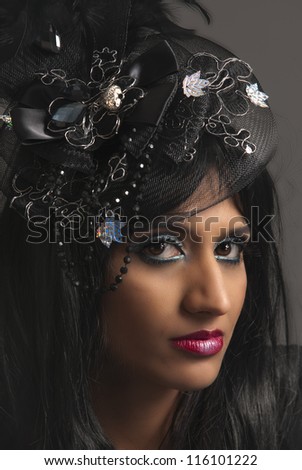 Beautiful dark haired woman with dark makeup and black and silver hat