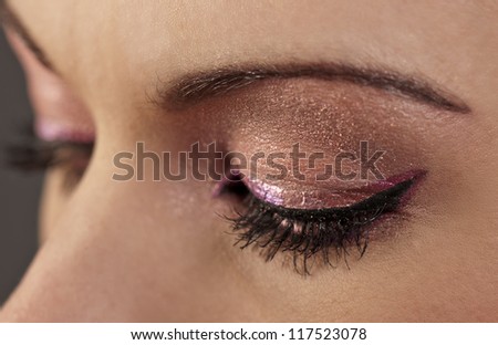 Woman's closed eyes with graphic pink and purple makeup
