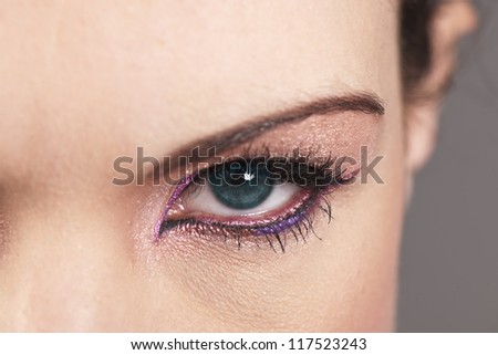 Beautiful woman's green eye with graphic pink colored makeup