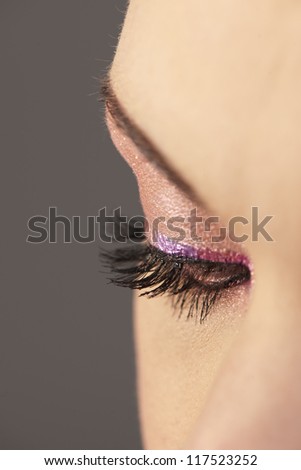 Profile view of beautiful woman\'s downwards looking right eye with graphic pink makeup and long lashes
