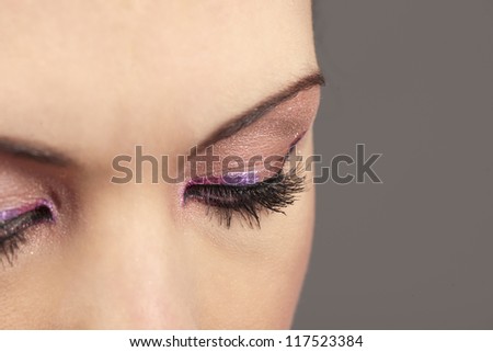 Close-up of beautiful woman\'s downward looking eyes with pink  graphic makeup