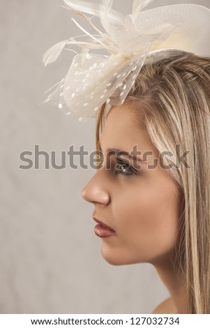 Portrait in profile of beautiful blonde girl with cream head dress