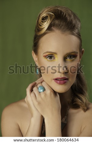 Portrait of beautiful blonde woman with colorful makeup and retro hairstyle wearing turquoise jewelry