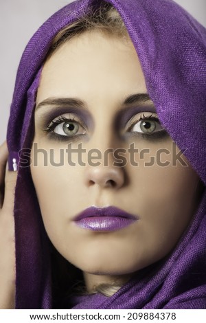 Stunning woman with purple makeup, headscarf and nail polish
