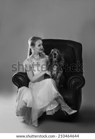 Monochrome portrait in black and white of beautiful blonde woman on leather couch with spaniel dog on her lap