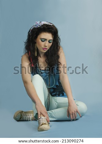 Sexy young woman with her brown hair styled in a wild eighties hairstyle with bow, wearing colorful eighties style makeup, nail polish, and clothing