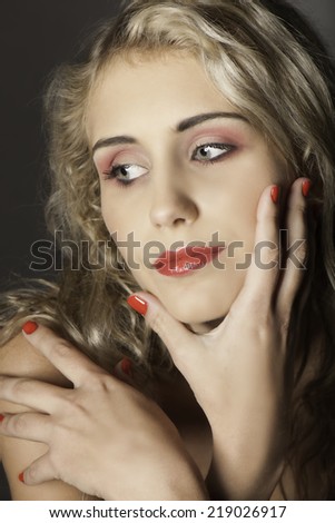 Portrait of pretty blonde woman with messy hairstyle, red makeup and red nail polish