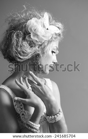 Monochrome portrait of beautiful blonde woman with fantasy makeup and hairstyle, wearing pearl jewelry and false eyelashes