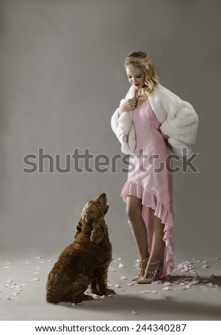 Socialite in pink wearing heels and coat looking down at her Spaniel dog