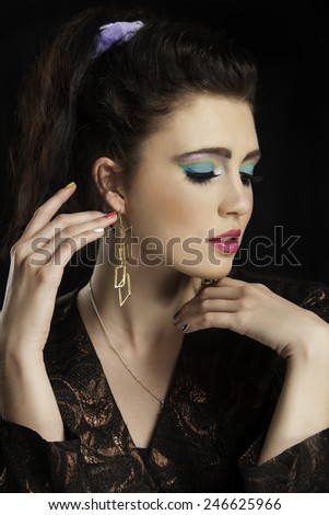 Portrait of  beautiful eighties woman with ponytail wearing colorful makeup who is looking to the side.
