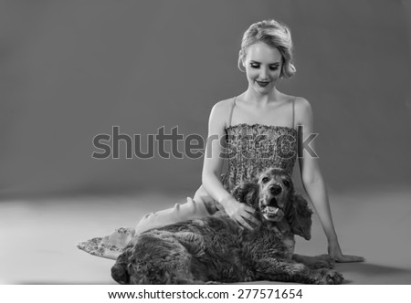 Beautiful blonde woman seating on ground with adorable dog in black and white