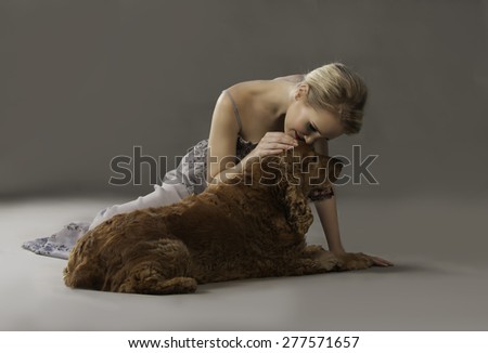 Beautiful blonde woman kissing a cute spaniel dog on its head
