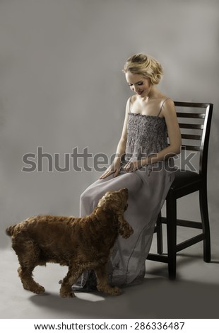 Attractive blonde woman looking down at the cute dog at her feet