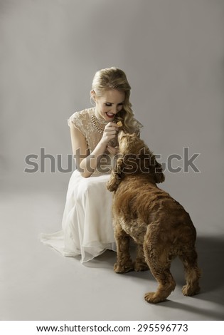 Pretty blonde woman holding a treat for her cute dog