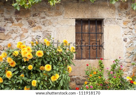 Stone facade with window. Stone ancient facade with wooden window and beautiful colored flowers