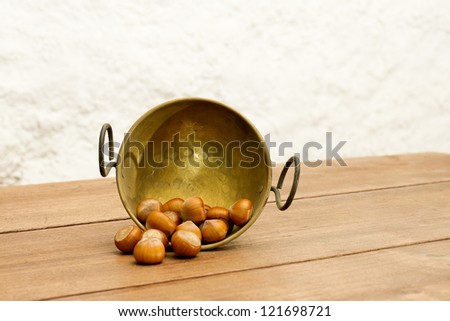 Bowl of Chestnuts. Autumnal arrangement with a bronze bowl of chestnuts on wooden table