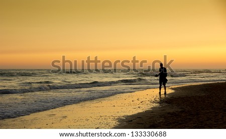 Golden sunset on the beach. Man walking on the beach at sunset. A silhouette of a man enjoying a beautiful golden sunset