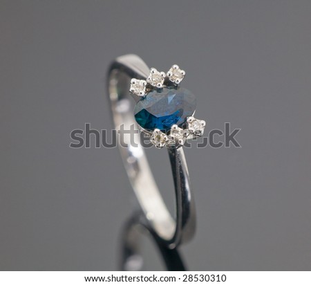 Beautiful white gold ring with blue sapphire on grey background