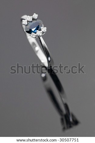 Beautiful white gold ring with blue sapphire on grey background