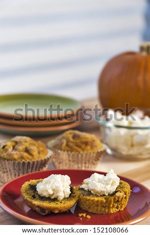 A traditional fall food, fresh baked pumpkin muffins are served with cream cheese.  One image in a series.