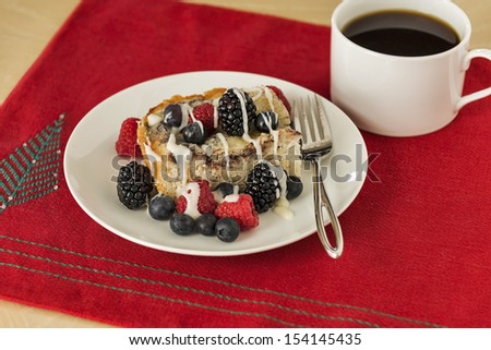 Coffee cake with fresh berries and a cup of black coffee on a Christmas placemat.  Room for copy space in bottom right corner.
