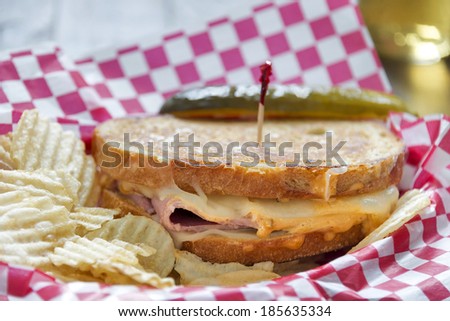 Grilled deli style Reuben sandwich served with potato chips and a dill pickle.  Selective focus was used on this image.