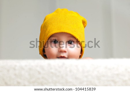 Cute Baby With a Beanie Hat, behind a sofa