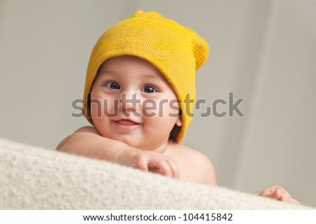 Cute Baby With a Beanie Hat, behind a sofa