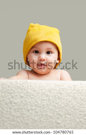 Cute Baby With A Beanie Hat Looking Behind A Sofa