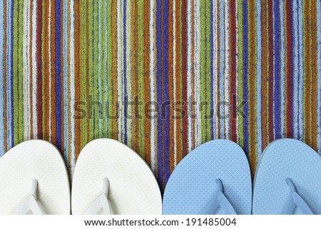 Flip flops sit atop a brightly colored striped beach towel
