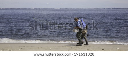 SANDY HOOK, NJ - SEPTEMBER 6: Two fishermen walk along the beach with their fishing gear. Photo taken September 6, 2013.
