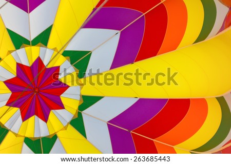 A photograph taken from inside a hot air balloon shows the vibrant colors and patterns of its design.
