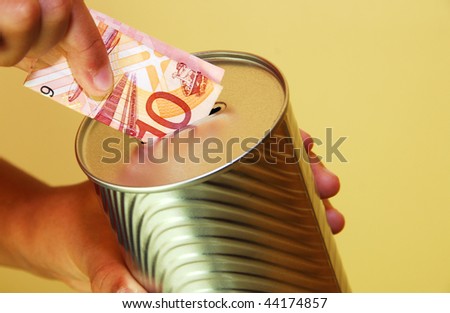 a person inserting a  malaysian ten dollar dote in to a silver colored tin can