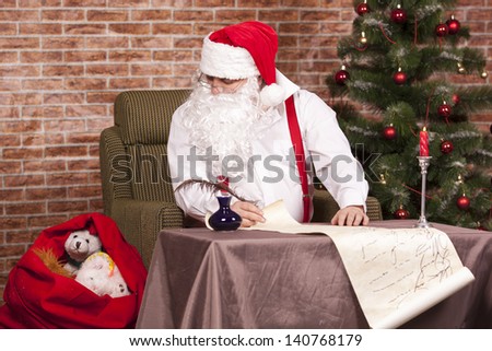 Santa Claus writes a list on the background of the Christmas tree