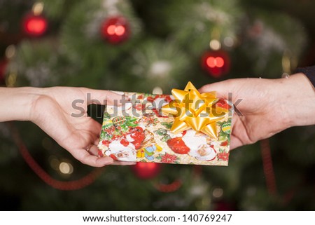 Gift delivery  between a man and a woman in front of Cristmas tree